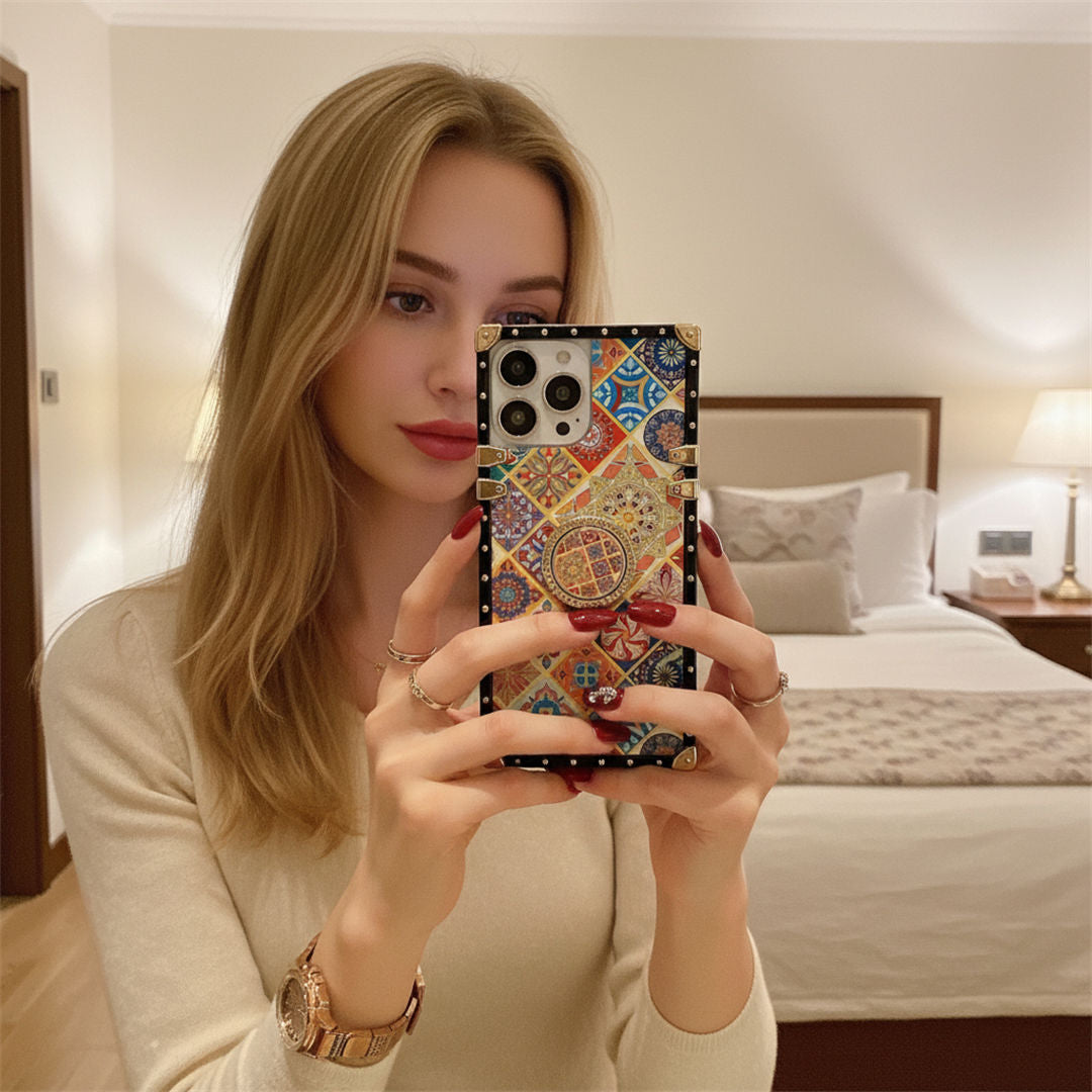 Woman holding a phone with a colorful case in a bedroom setting