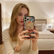 Woman holding a phone with a colorful case in a bedroom setting