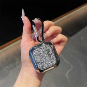 Hand holding a glittery case with a carabiner against a blurred background