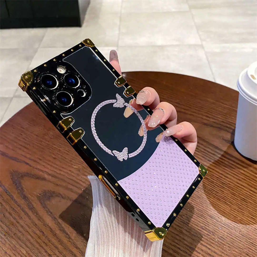 Phone case with decorative design held by a hand on a wooden table.