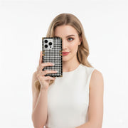 Woman holding a phone with a black and white patterned case against a white background