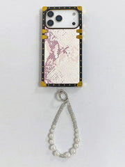 Phone case with pink glittery design and gold accents, featuring a beaded charm on a light gray background.