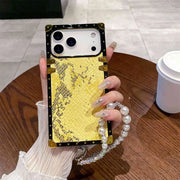 Phone case with gold and black design held by a person with a pearl bracelet.
