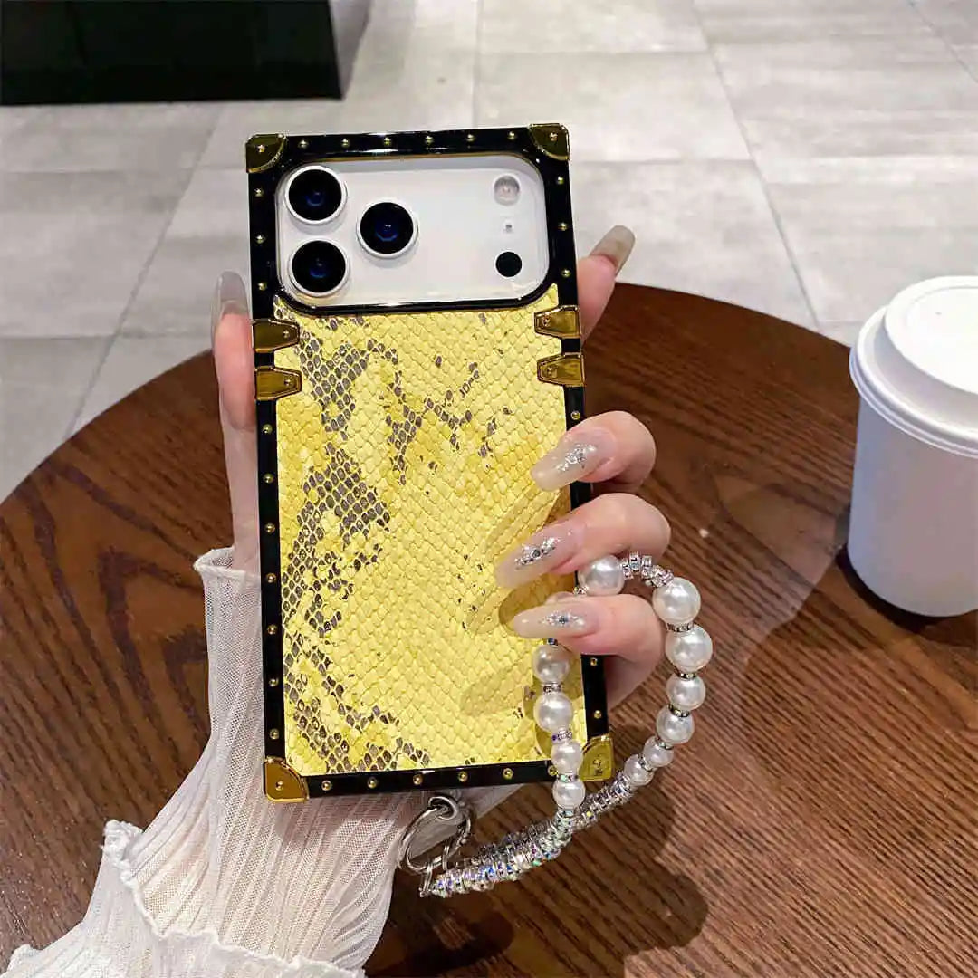Phone case with gold and black design held by a person with a pearl bracelet.