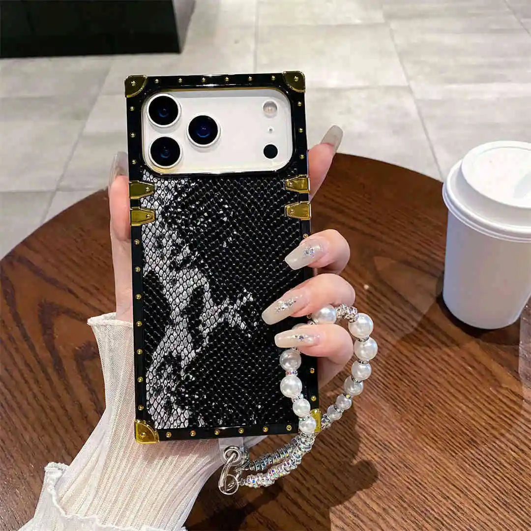 Person holding a phone case with decorative elements on a wooden table.
