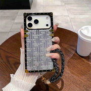Phone case with geometric pattern held by a hand on a wooden table.