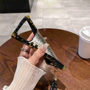 phone cae with gold accents held by a hand on a wooden table.