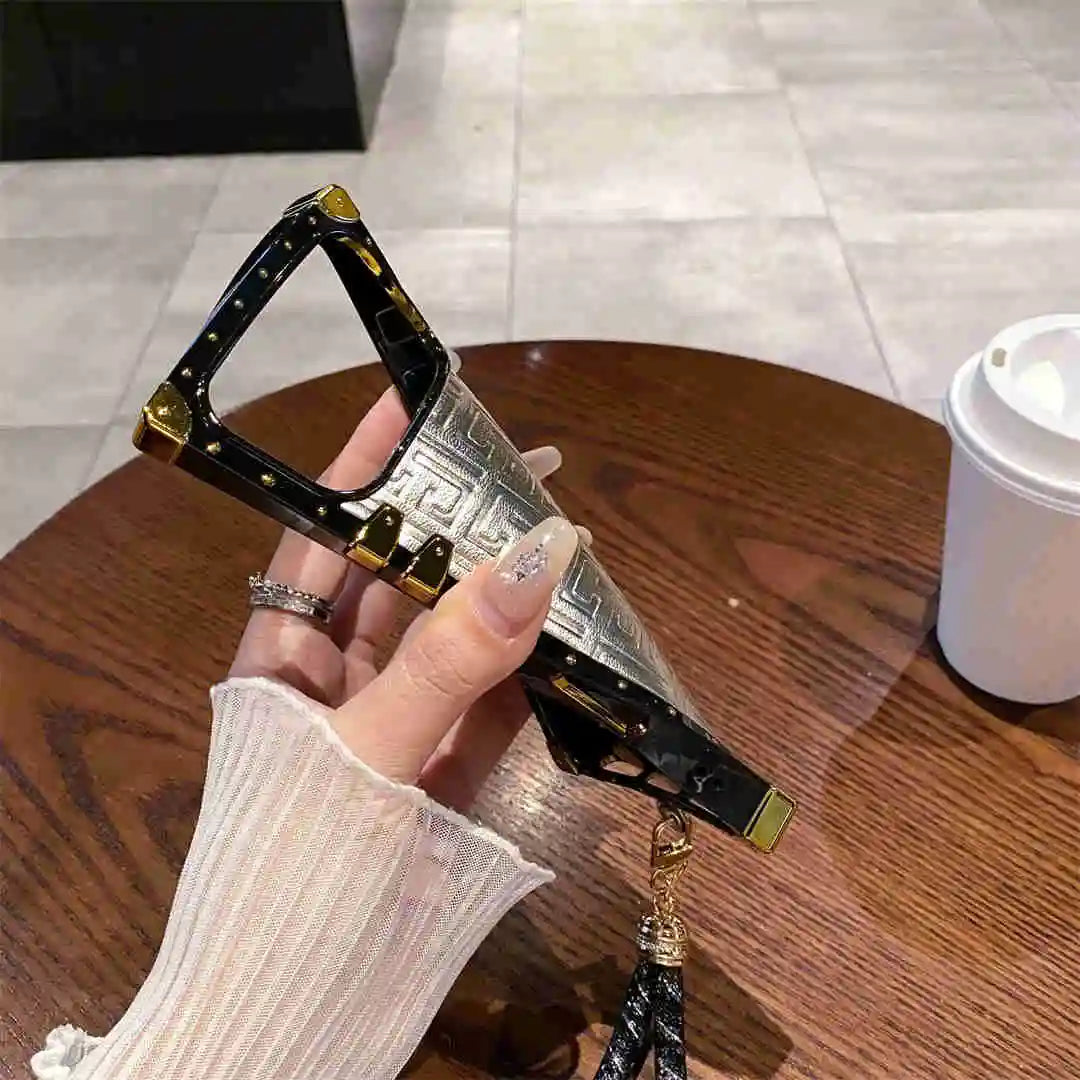 phone cae with gold accents held by a hand on a wooden table.