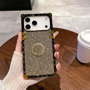Glitter square Phone case with rhinestone details held by a hand on a wooden table.