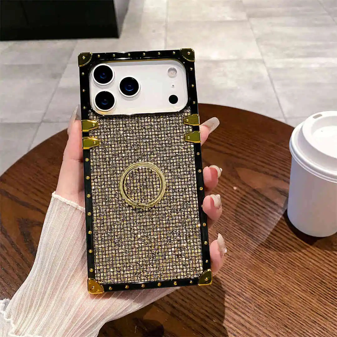 Glitter square Phone case with rhinestone details held by a hand on a wooden table.