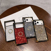Four glittery phone cases on a wooden surface with a paper underneath.