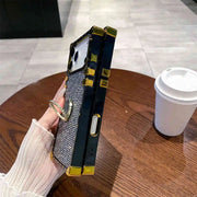 Luxury phone case with gemstones held by a hand on a wooden table.