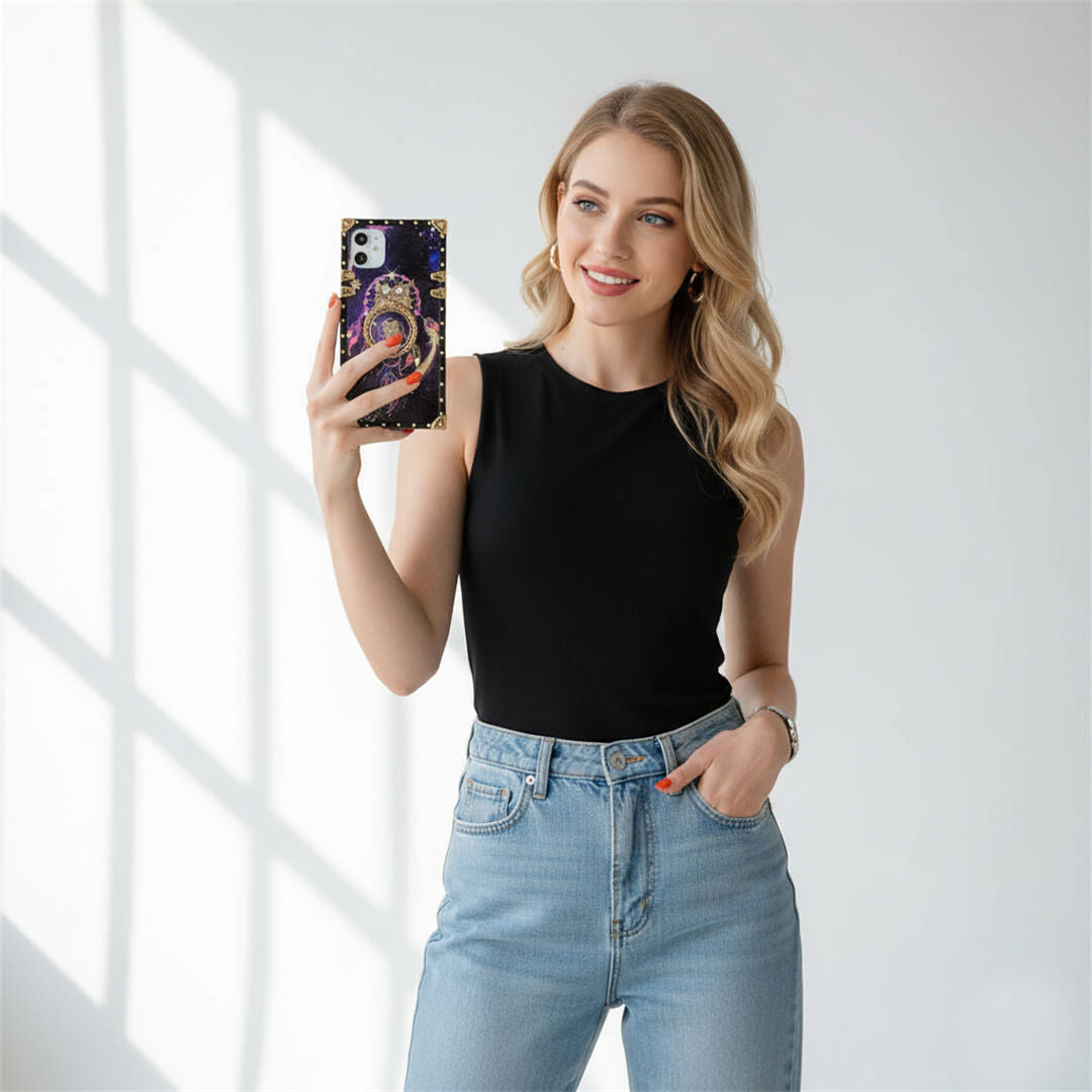 Woman taking a selfie wearing a black sleeveless top and blue jeans in a bright room.