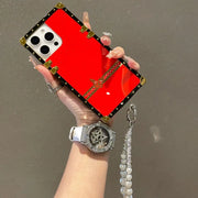 Hand holding a red phone case with decorative elements against a neutral background
