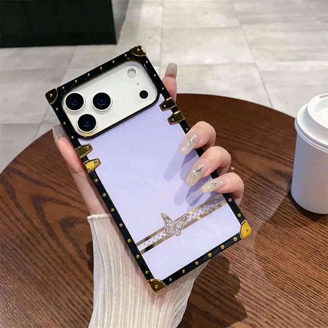Phone case with decorative elements held by a hand on a wooden table.