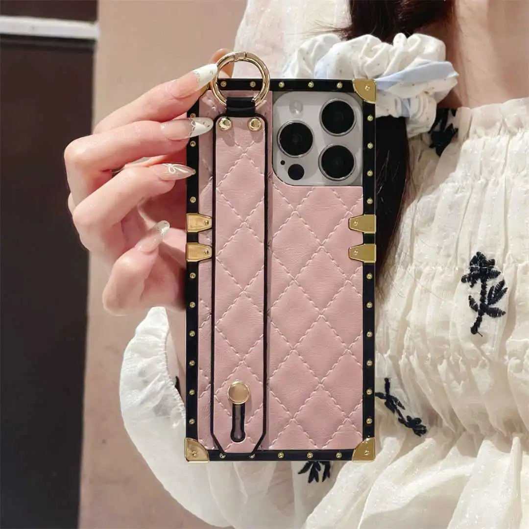 Pink quilted phone case with gold accents held by a person wearing a white outfit.