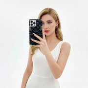 Woman holding a phone with a black soft leather iPhone case against a white background