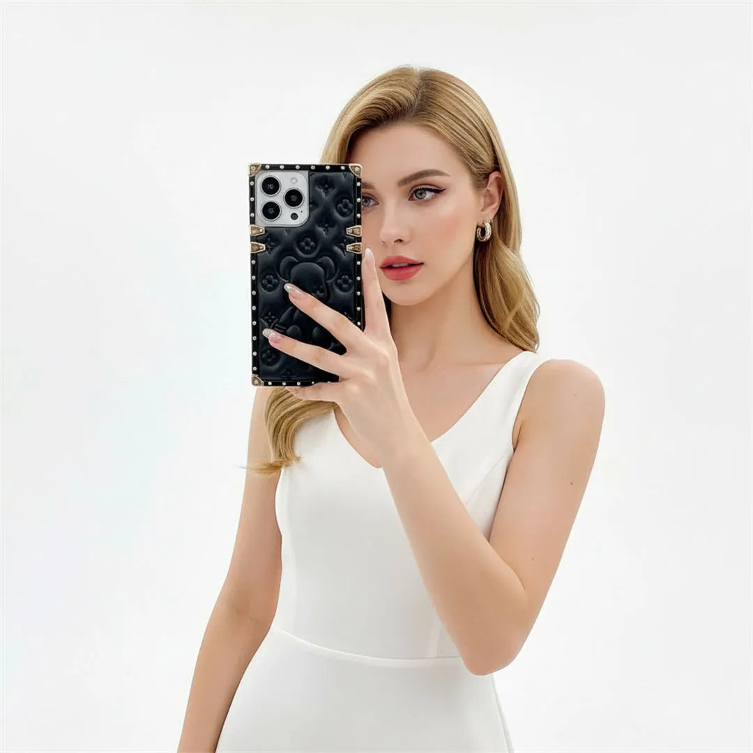 Woman holding a phone with a black soft leather iPhone case against a white background