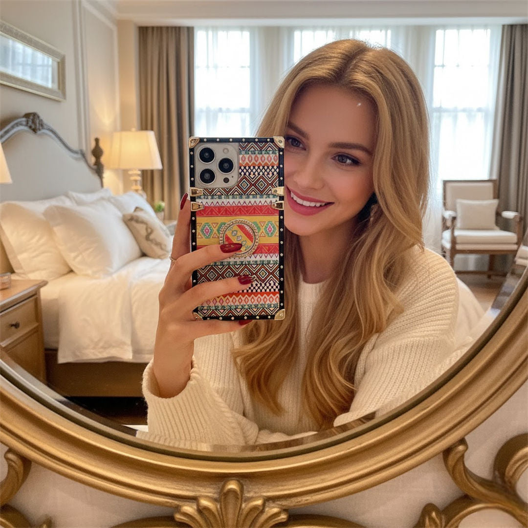 Woman holding a phone with a colorful case in front of a mirror in a bedroom.