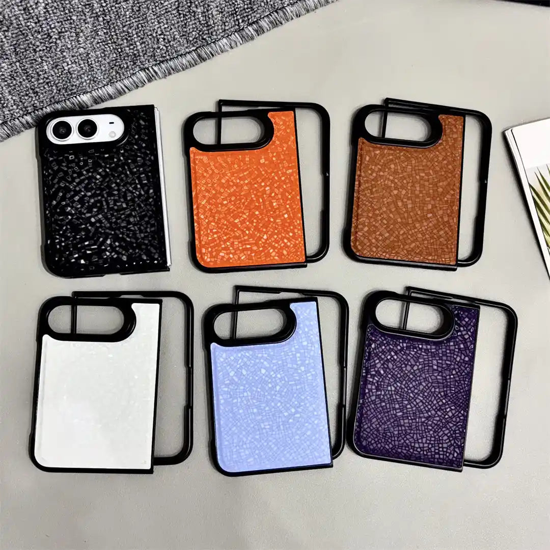 Six smartphone cases arranged in two rows on a light surface. The cases have black frames and back panels with a glittery texture, shown in black, orange, bronze, white, light blue, and purple.