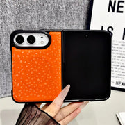 An orange phone case with a textured pattern of small white icons, shown on a smartphone held in a hand. The phone is partially folded, revealing a black inner screen or back panel.