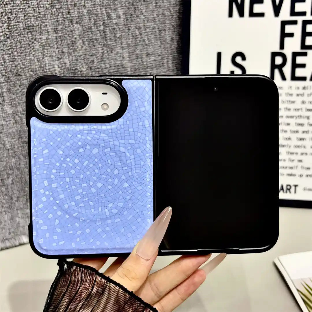 A light blue mosaic-patterned flip phone case with a black border, held open in a hand against a gray textured background.
