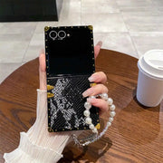 Person holding a black phone case with decorative elements on a wooden table.