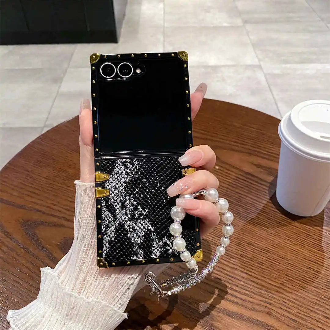 Person holding a black phone case with decorative elements on a wooden table.