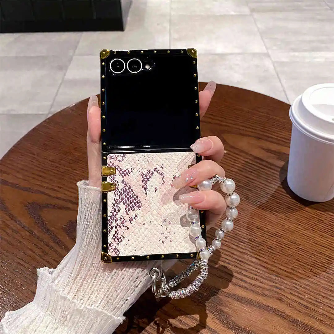 Person holding a phone case with snake print design on a wooden table.
