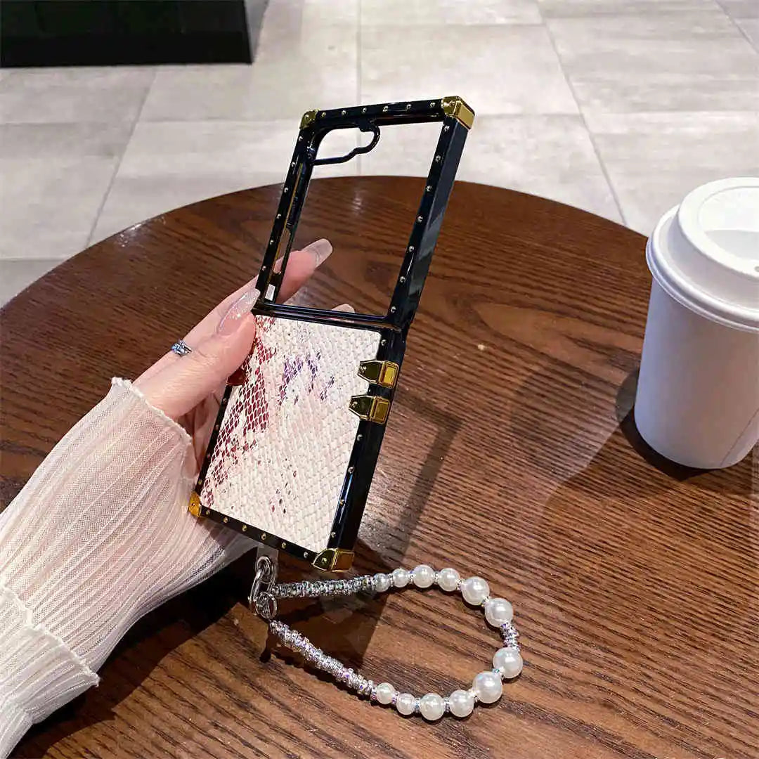 Phone case with snake skin pattern held by a hand on a wooden table with a coffee cup in the background.