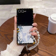 Person holding a phone with a decorative case on a wooden table.