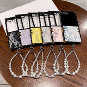 Set of phone cases with various designs and pearl necklace charms on a wooden surface.