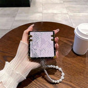 Hand holding a phone case with a textured design on a wooden table with a coffee cup.