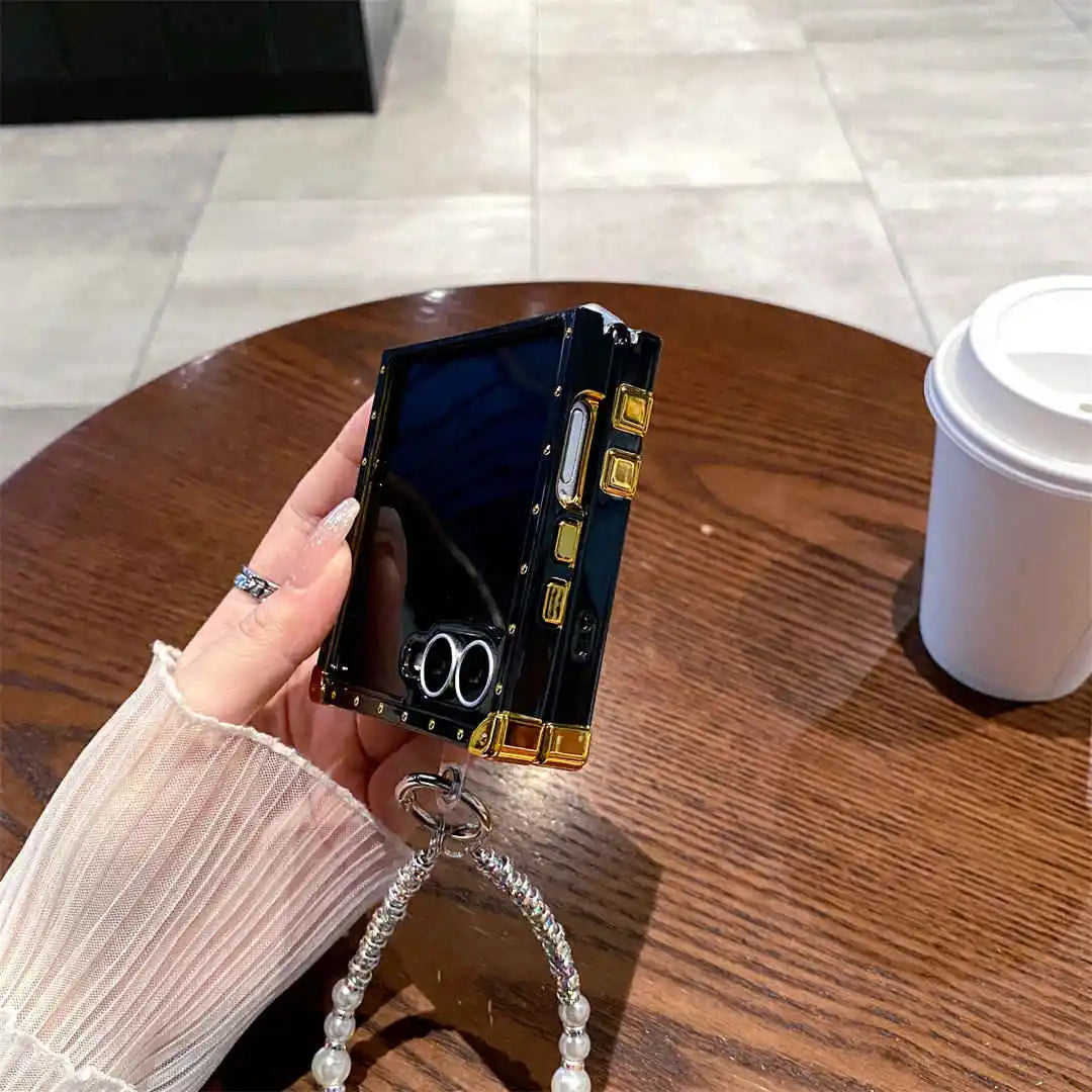Hand holding a small foldable phone on a wooden table with a cup in the background