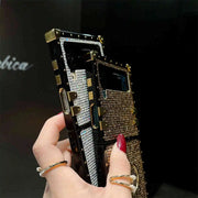 Hand holding a intricately designed phone case with rhinestones against a dark background