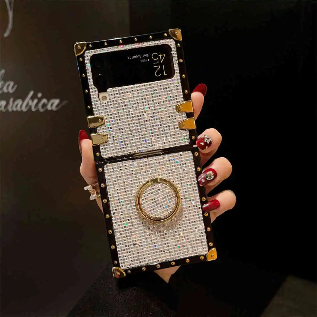 Hand holding a decorative phone case with gemstones and a ring display.