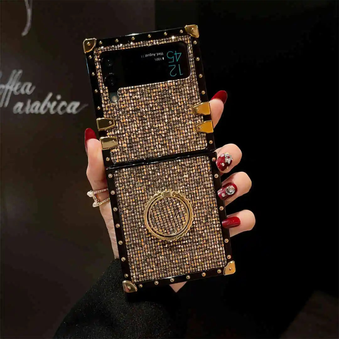 Hand holding a smartphone with a decorative case featuring gold accents and gemstones.