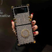 Phone case with rhinestones held by a hand with red nail polish against a dark background