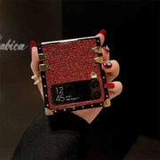 Hand holding a red and gold phone case with a black background