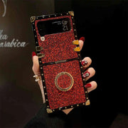 Hand holding a red embellished phone case with gold accents against a dark background
