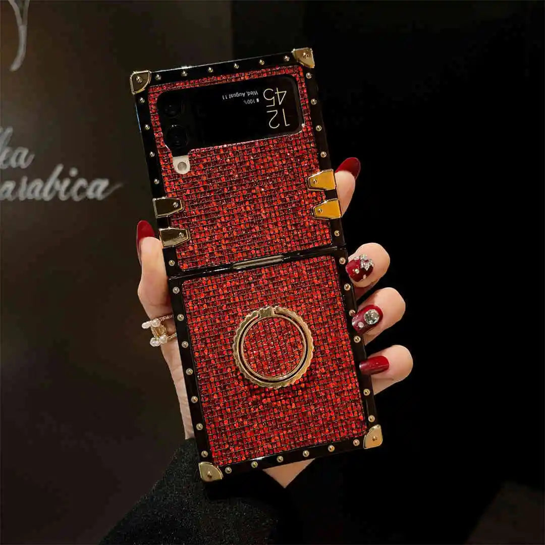 Hand holding a red embellished phone case with gold accents against a dark background