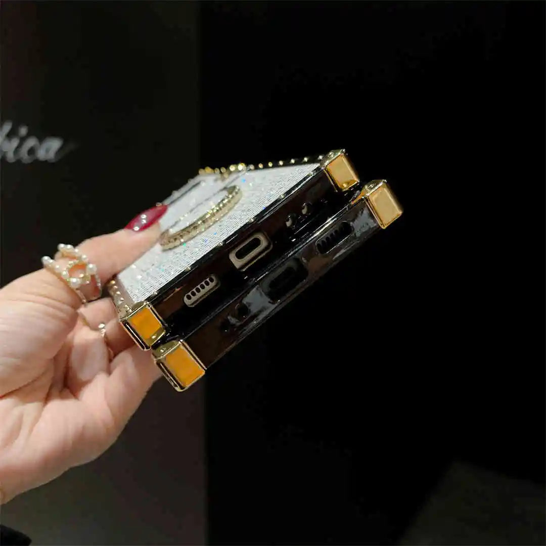 Phone case with decorative elements held by a hand against a dark background