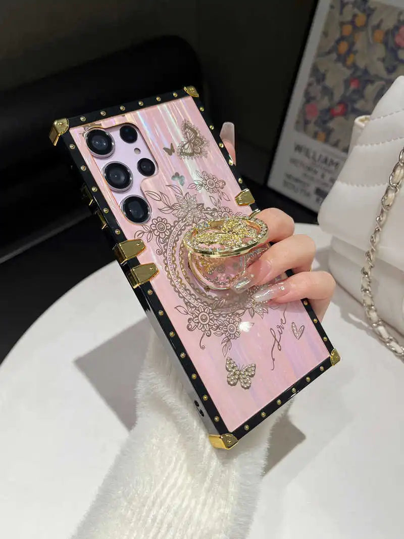 Hand holding the pink Aurora Galaxy Trunk Samsung case with the butterfly ring holder raised