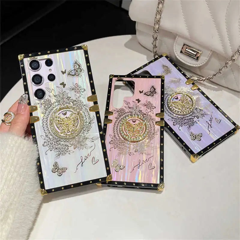White, pink and purple Aurora Galaxy Trunk Samsung cases displayed together beside a handbag