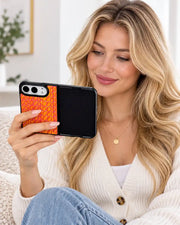 Woman viewing an open iPhone Duo in the orange Prism Scale Duo case