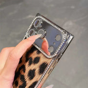Close-up of the brown Leopard Chrome Spark iPhone case showing its reflective camera panel and rhinestone edging