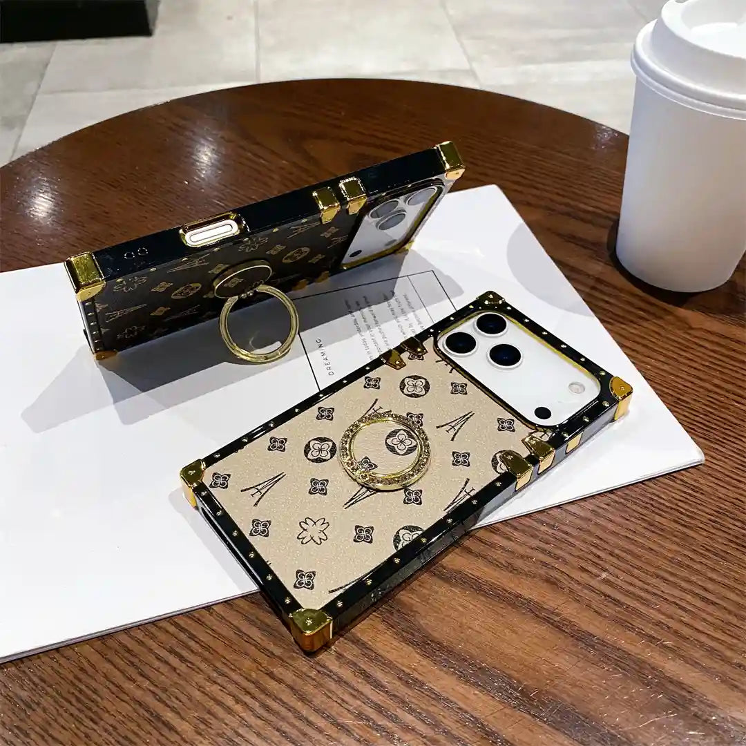 Brown Paris Monogram Trunk iPhone case propped on its ring stand beside the beige version on a table