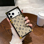 Hand holding the beige Paris Monogram Trunk iPhone case beside a coffee cup