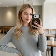 Woman in a gray sweater taking a selfie with the brown Paris Monogram Trunk iPhone case