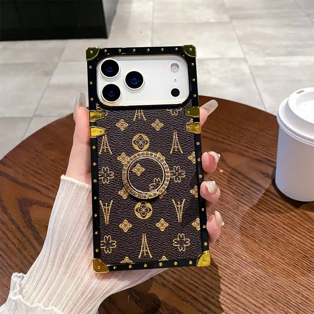 Brown Paris Monogram Trunk iPhone case held upright, showing monogram pattern and ring holder